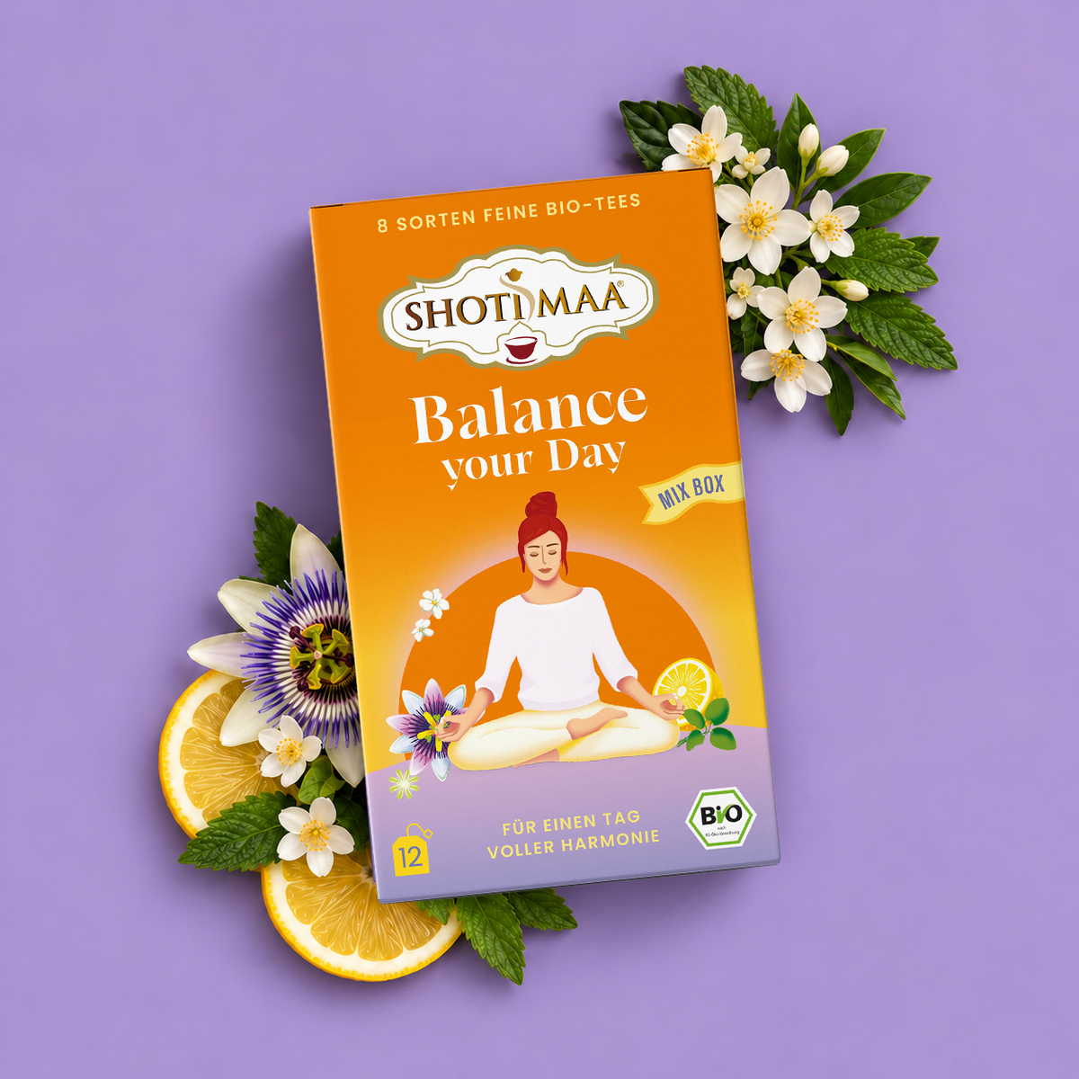 A box of Shotimaa 'Balance your Day' organic fine-leaf tea is displayed on a lavender background, styled with orange slices, white flowers, and green leaves.