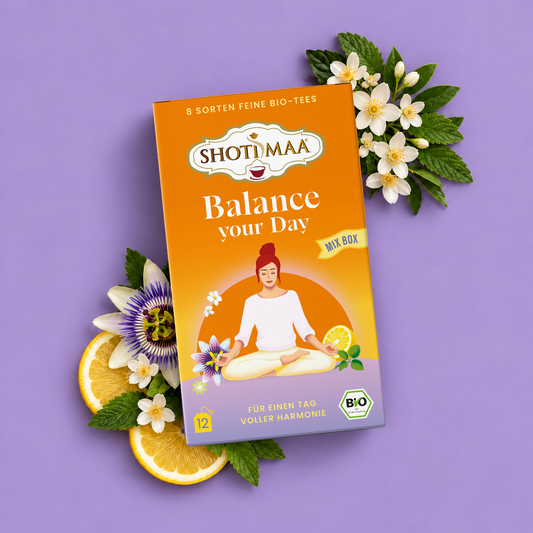 A box of Shotimaa 'Balance your Day' organic fine-leaf tea is displayed on a lavender background, styled with orange slices, white flowers, and green leaves.